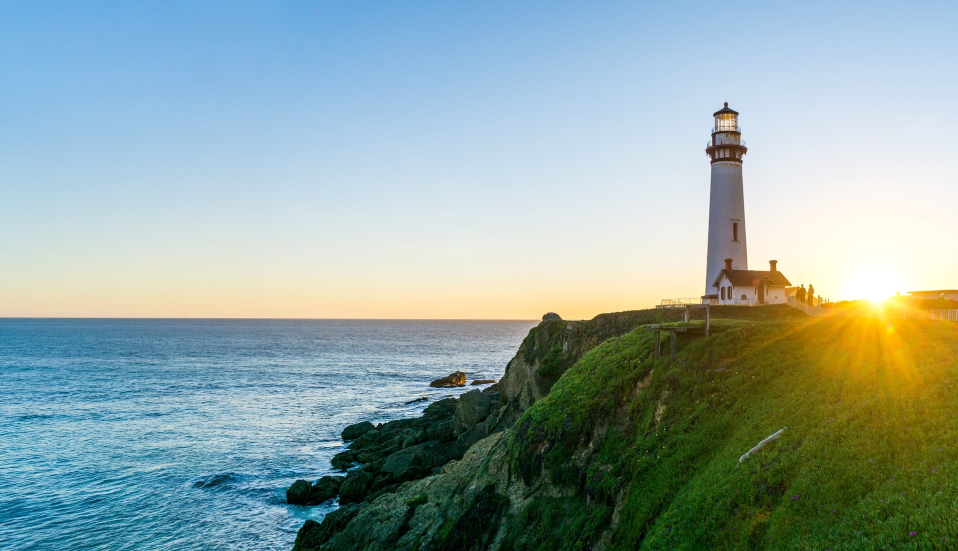 Lighthouse overlooking water at sunrise