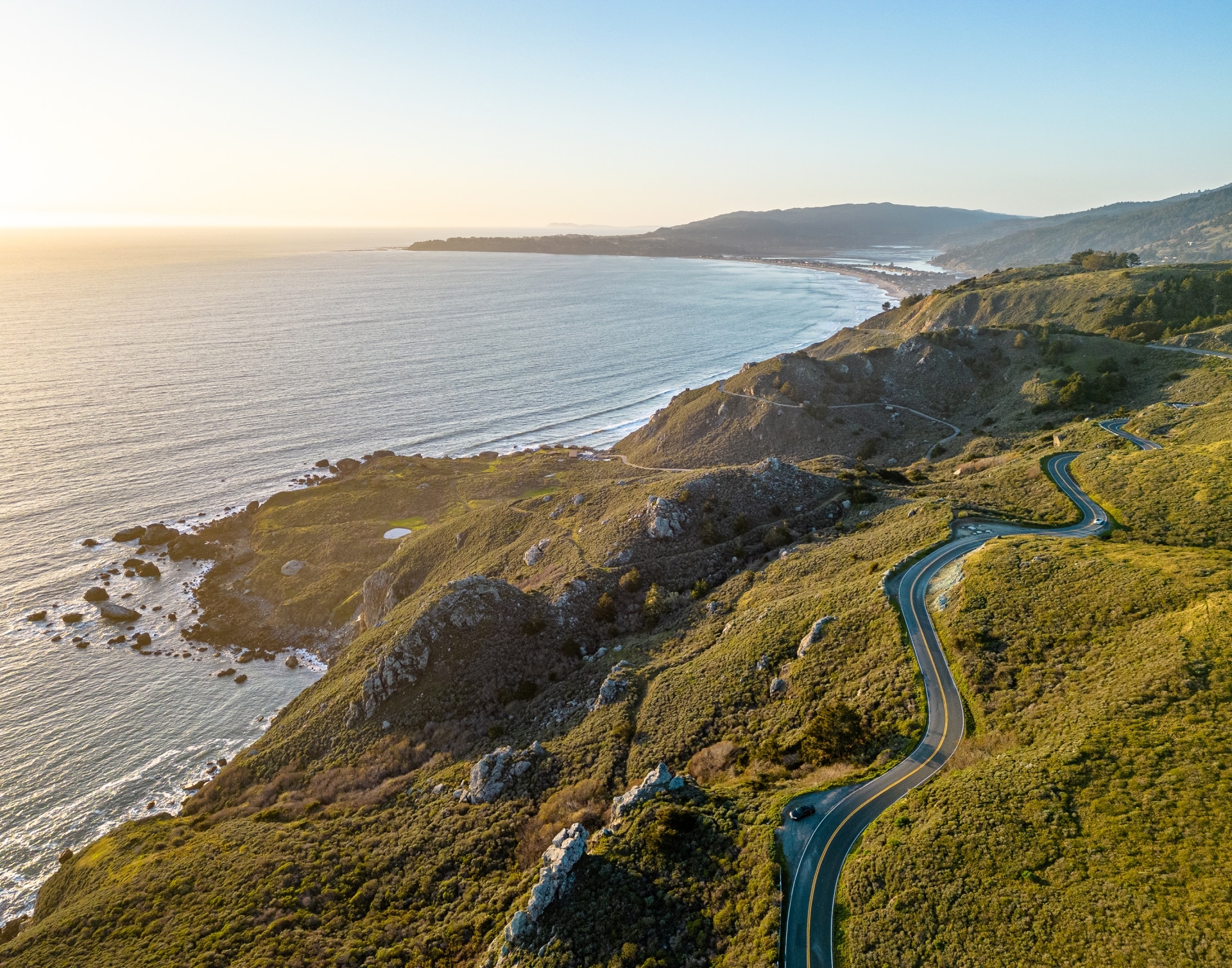 aerial view of southern California Route 1 along green hills next to ocean